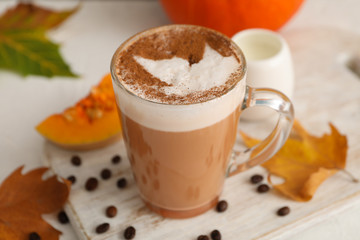 Composition with glass cup of pumpkin latte on white background