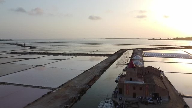 Panoramic View Of The Iconic Windmill And Vast Salt Pans At The Sea Coast In Mazara Del Vallo, Sicily, Italy On A Sunrise - aerial drone - panning shot