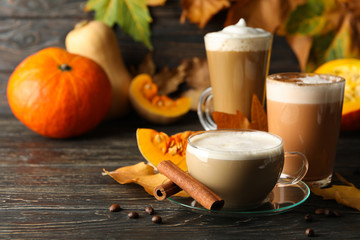 Composition with pumpkin latte, cinnamon and pumpkin on wooden background