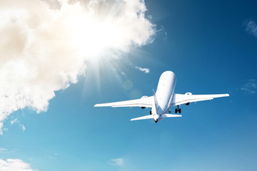Civil plane took off into the blue sky and flies away into the bright rays shine the sun in the...