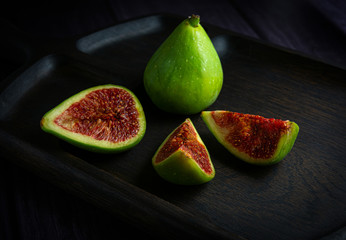Ripe green figs whole and sliced on a dark wooden Board