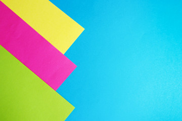 abstract background pink, yellow and green paper on blue.. copy space.