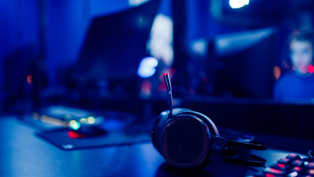 Cyber sport workplace, headphones and gaming keyboard with monitor. Blue tinted esport