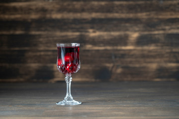 Homemade tincture of red cherry in a wine crystal glass on wooden background, Ukraine