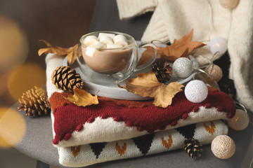 Autumn concept with sweaters, cup of coffee and blurred lights