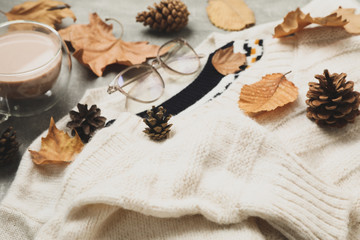 Concept of autumn wear with sweaters and coffee on gray background