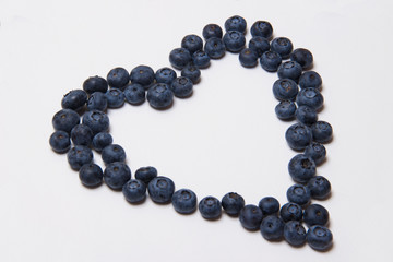 group of blueberries on white wooden background in form of heart