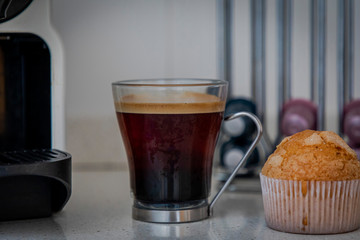 A cup of coffee from a coffee machine and a muffin