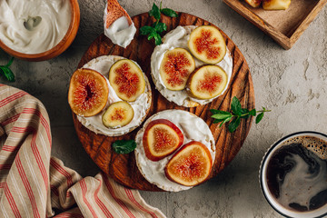 Healthy snack wholegrain rice crispbread crackers, figs and ricotta cheese on a wooden board.