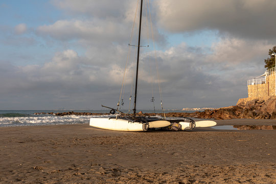 A catamaran or Hobie cat boat stands in a Spanish beach