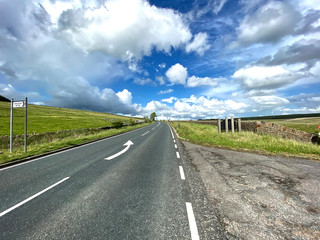 Fototapeta premium The A6068 Colne to Cowling road, with broken cloud, and green fields near, Cowling, Keighley, UK