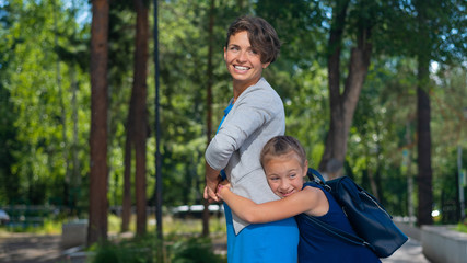 Fototapeta premium Excited schoolgirl hugs mom behind her back. The girl missed her mother very much.
