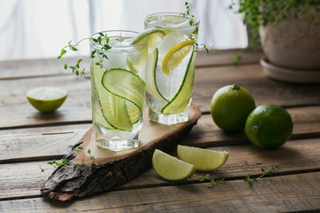Glass of cucumber cocktail or mocktail, refreshing summer drink with crushed ice and sparkling water on a wooden background
