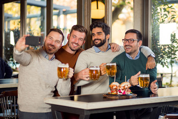 Group of male friends make selfie in beer pub