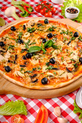 Rustic pizza with chicken meat, cheese, tomato, olive, mushrooms and tomatoes sauce, served on a wooden board for a dinner in italian restaurant background, top view. Classic Italy food. Close up