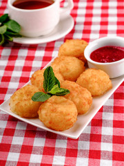 Doughnuts. Freshly made donuts from cottage cheese with berry jam and black tea on breakfast. Balls from the cottage cheese, the dessert on white plate in restaurant background, top view.