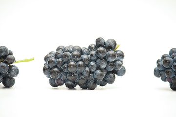 Isolated small bunch of dark technical grapes lying on its side on white background