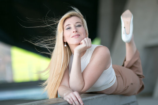 Joven Mujer Feliz Rubia Posando En Un Muro Con Pantalon Marron Y Zapatos Blancos