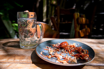 an empty glass of beer and the remains of crayfish on a plate that someone has already eaten