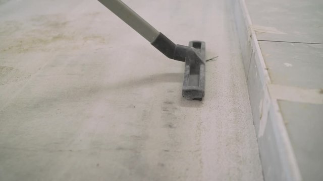 A Cleseup worker vacuums a public concrete floor. Cleaning for a good hygiene concept. A worker vacuums the floor in preparation for sanding. Preparing the concrete floor for mixing. Industrial vacuum