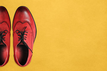 Boots of red color made of genuine leather on a yellow background. Brown shoes close-up with a copy...