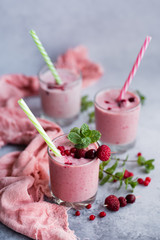 Glasses of berry smoothie on light background.