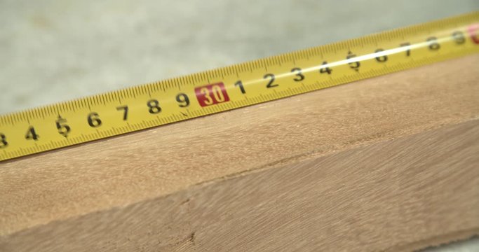 Measuring the size of the wooden board with a tape measure in centimeters seen from above 4k video