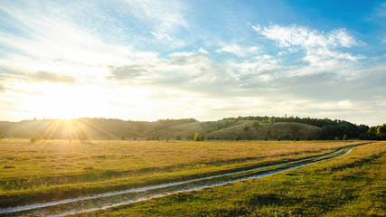 Obraz premium Summer landscape with green field cloudy sky and hills on the background