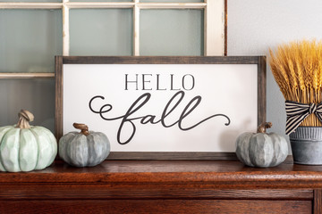 Hello fall sign and neutral colored pumpkins on wood mantel