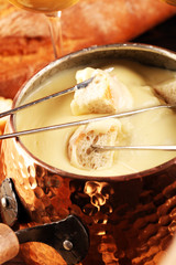 Gourmet Swiss fondue dinner on a winter evening with assorted cheeses on a board alongside a heated...
