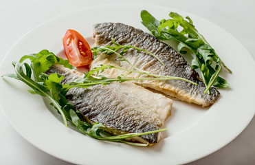 Sea bass fillet fried on a plate, seafood.