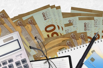 50 euro bills and calculator with glasses and pen. Tax payment concept or investment solutions....