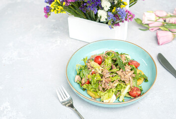 Mediterranean salad on the light stone table decorated with flowers