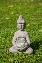 Buddha statue on the natural background. Sunny morning in the park.  Summer background for meditation and relaxation