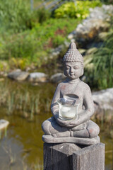 Buddha statue on the natural background. Sunny morning in the park.  Summer background for meditation and relaxation