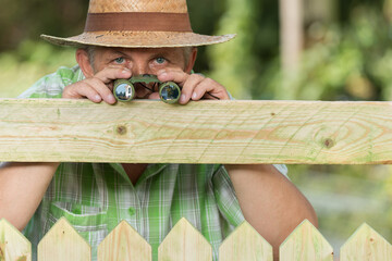 Curious neighbor stands behind a fence and watches