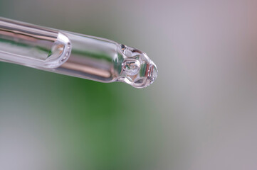 Glass tube, pipette with solution, serum. Serum dialed for use. Serum for skin care. The solution is collected in a glass pipette. Transparent solution.