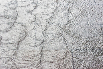 Textured surface of city fountain water flowing on concrete pavement.