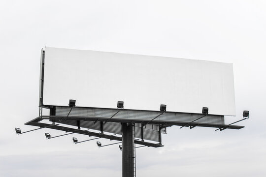 Large mega board, commercial billboard with empty blank space and light on gray sky background.