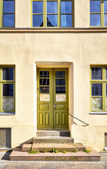 Fototapeta na wymiar Light green wooden door and window as an entrance in an old house.