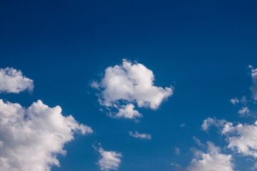 Fototapeta premium Clouds in the blue sky. Sunny day. Clouds floating across the sky. The clouds are illuminated by the sun's rays.