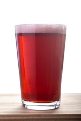 A pint glass of red beer on a wooden table over white background