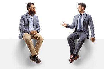 Two men sitting on a white panel and having a conversation