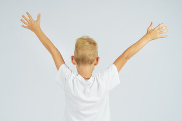A portrait of a schoolboy who turned away from the camera and held his hands up. Isolated background.