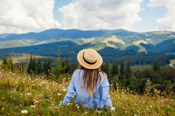 Traveling in summer Ukraine. Trip to Carpathian mountains. Woman tourist relaxing in flowers...