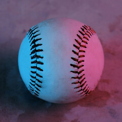 Baseball ball close up with glow of lights in pink and blue for pop of color.