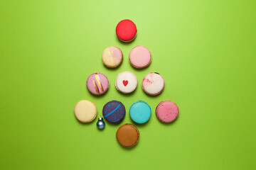 Sweet colorful french cookies (macaron or macaroon) laid out on green background in the shape of a christmas tree, top view. Merry Christmas card concept for greeting