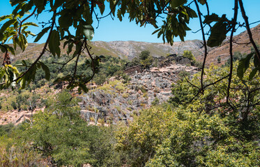 Drave stone houses and cross view with tree leaves foreground