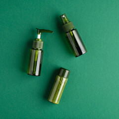 Natural skincare cosmetic bottles on green background. Bio beauty products packaging design. Flat lay, top view.