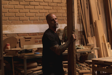 Hombre maduro mexicano trabajando carpintero en taller con madera tabla sierra martillo 